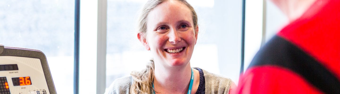 A woman wearing a Mercy Health lanyard smiles at a patient who is on a machine.