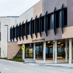 A long shot of the drive in entrance to the Clare Moore Building. A sign nearby directs towards Outpatient Clinics and Mental Health Unit.